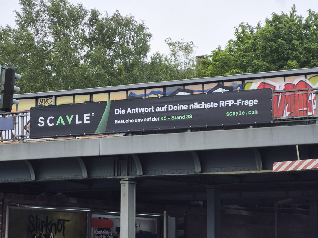 Brückenwerbung an einer Bahntrasse für Scayle, in den Farben weiß und grün.