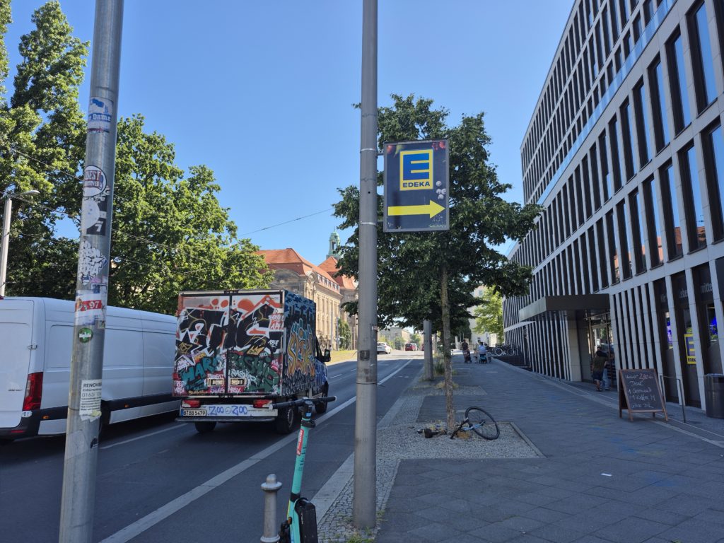 Mastenschild mit Hinweis zum nächsten Supermarkt.