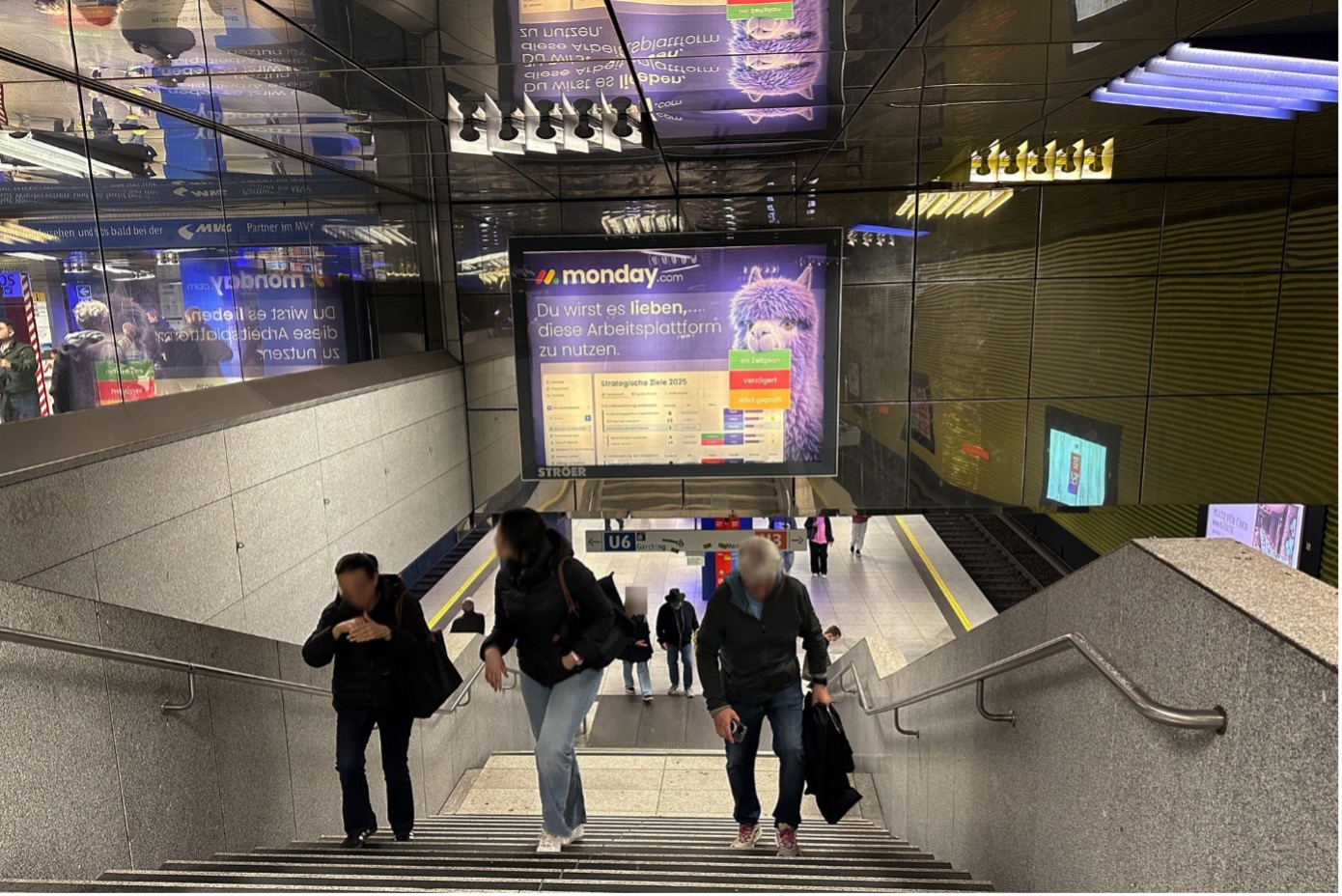 Leuchtwerbung an einem U Bahnhof, wirbt mit einem lila Lama für Monday.com.