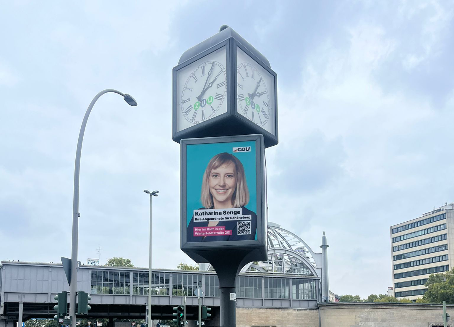 Uhrenwerbung in Großaufnahme, mit Außenwerbung für die CDU.